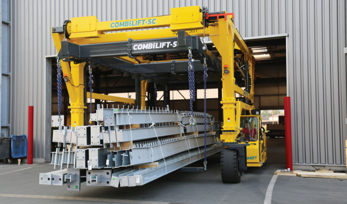 Yellow Combilift Straddle Carrier ready to lift red storage container